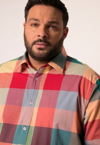 Camisa de cuadros multicolores con cuadrados rojos, melocotón, verdes y azules. Hecha de una tela ligera, con cuello de botón y acentos rojos.