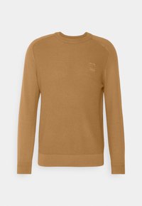 Men’s long-sleeve camel brown knit sweater with crew neck and textured front panel, featuring a small square logo patch on the chest.