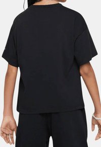 Camiseta negra de manga corta hecha de algodón, con cuello redondo, corte relajado y costuras mínimas. Tejido texturizado con costura directa.