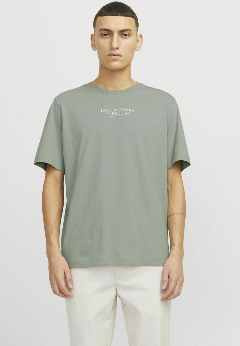 Šviesiai žalia medvilninė marškinėliai su trumpomis rankovėmis ir apvaliu iškirpimu. Ant krūtinės pavaizduotas baltas "Jack & Jones Premium" logotipas.
