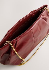 Bordeauxrode leren handtas met een gladde textuur, een geplooid ontwerp en een goudkleurige kettingriem. Voorzien van een binnenvak met rits.