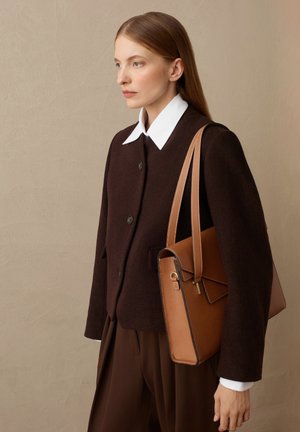 Veste en laine marron avec un col blanc et des détails de boutons, accompagnée d'un sac à main en cuir beige avec un rabat et des accents de couture.