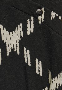 Tissu noir avec un motif abstrait blanc. Comprend un petit bouton en métal gravé "Street One". Texture lisse, design distinct.