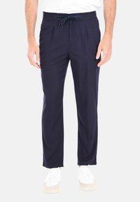 Pantaloni blu navy con vita regolabile, fronte plissettato e vestibilità rilassata. Realizzati in tessuto leggero, con una texture morbida e un design minimal.