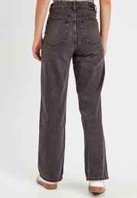 Jeans de mezclilla gris de pierna ancha con cintura alta, que cuentan con bolsillos traseros y un ajuste holgado. Terminados con una textura sutil y dobladillos remangados.