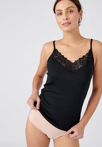 Top negro sin mangas con ribete de encaje en el escote, con tirantes finos ajustables. Modelo combinado con ropa interior lisa de color nude.