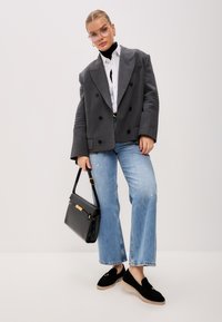 Grey double-breasted blazer, white shirt, black turtleneck, light blue wide-leg jeans, black handbag, and black shoes with a light sole.
