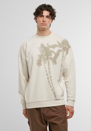 Lys beige sweatshirt med et stort palmetræ-graphic i en mørkere beige tone. Lavet af blødt stof med en afslappet pasform og ribbede manchetter.