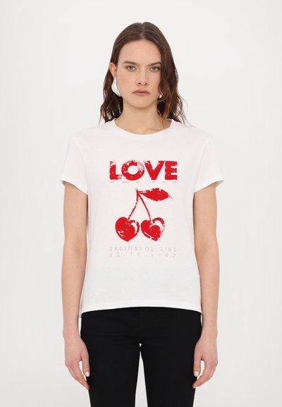 Bijela pamučna majica s kratkim rukavima. Crveni natpis "LOVE" i grafika trešnje otisnuti na prednjoj strani. Uparen s crnim hlačama.