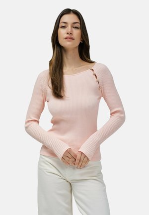 Top de manga larga acanalado en algodón color rosa claro, con un escote amplio y botones decorativos en el hombro. Combinado con pantalones blancos.