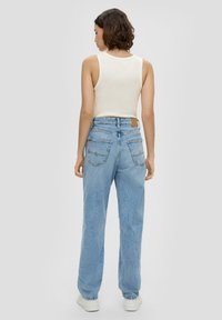 Helles beige ärmelloses Top, kombiniert mit hellblauen, hochgeschnittenen Jeans aus Denim mit lockerer Passform und dezentem Stichdetail an den Hintertaschen.