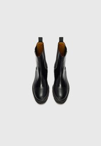 Bottines en cuir noir avec une finition lisse, bout rond, coutures contrastées et doublure intérieure marron ; elles sont dotées de tirettes à l'arrière.