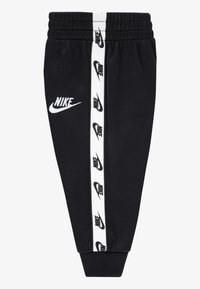 Fekete Nike melegítőnadrág elasztikus derékpánttal, keskenyedő szárakkal és fehér oldalsávokkal, melyeken ismétlődő fekete logók láthatók. Puha textúrájú anyag.