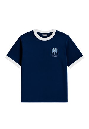 Junger Mann mit roter Kappe und dunkelblauem T-Shirt mit weißem Rand und Logo, kombiniert mit grauen Nadelstreifenhosen, vor weißem Hintergrund stehend.