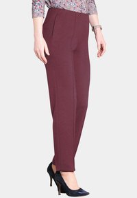 Bordeaux gepersonaliseerde broek van gladde stof, met zijzakken en een slim fit. Draagt met marineblauwe hoge hakken, met een puntige neus.