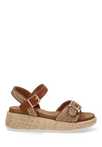Sandały brązowe na paski z plecioną cholewką i grubą podeszwą w stylu espadrille. Posiadają zapięcie na klamrę oraz teksturowaną, naturalną bazę z włókien.