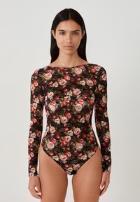 Florale kant bodysuit met een zwarte achtergrond, lange mouwen en een hoge hals. Rood, roze en groene bloemenpatroon verspreid over het geheel.