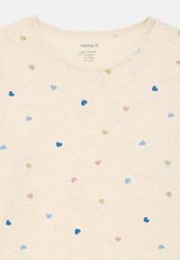 Beżowa koszula dziecięca z rozsianymi małymi sercami w kolorze niebieskim, zielonym, różowym i fioletowym, okrągły dekolt, metka rozmiaru widoczna wewnątrz kołnierza.