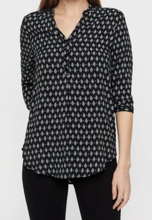 Musta paita, jossa on hienovarainen vaaleanharmaa pisarakuosi, kauluksellinen pääntie, kolme neljäsosaa hihaa ja kaartuva helma. Pehmeä kangaspinta.