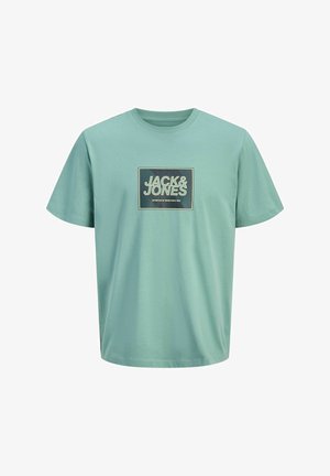 Világoszöld pamut póló kerek nyakkivágással, rajta egy téglalap alakú grafika, amelyen "JACK&JONES" felirat látható kontrasztos színekben.