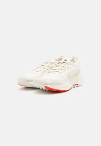 Lette løpesko i off-white mesh med teksturerte detaljer, med en distinkt rød gummisåle og støttende hældesign.