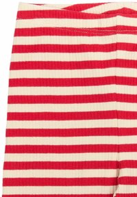 Piros és krém csíkos leggings, bordázott anyagból, puha derékpánttal és változó szélességű vízszintes csíkokkal.