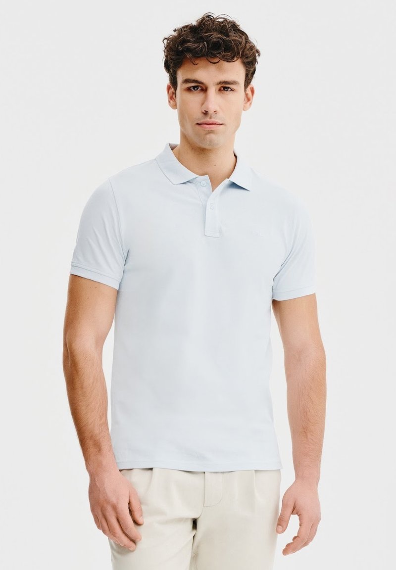 Jasnoniebieska koszulka polo z klasycznym kołnierzykiem, krótkimi rękawami i trzema guzikami. Posiada subtelne logo na piersi. Gładka faktura.