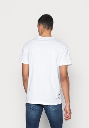 White cotton t-shirt with short sleeves, crew neck design, and a label detail at the hem. Smooth texture, casual fit.