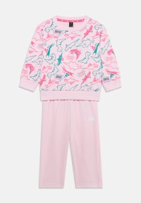 Sweatshirt rose et pantalon assorti avec un imprimé de dinosaure en vert et rose fluo. Tissu doux avec des poignets et une taille côtelés. Logo Adidas.