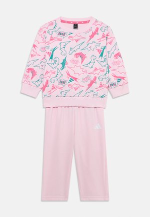 Rožinė džemperis ir jam derančios kelnės su žaliu ir neoninės rožinės spalvos dinozaurų spausdiniu. Minkšta medžiaga su gumuotomis rankovėmis ir juosmeniu. Adidas logotipas.