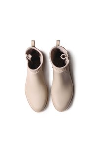 Stivali ankle impermeabili beige con texture liscia, punta rotonda e linguetta posteriore. L'interno presenta una fodera scura.