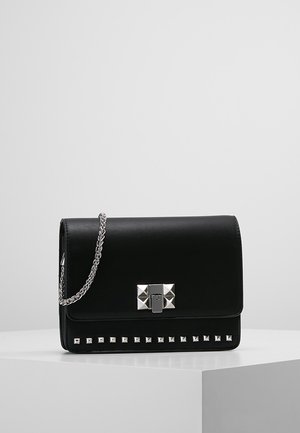 Czarna prostokątna skórzana torebka z srebrnym łańcuszkowym paskiem, srebrnymi piramidalnymi ćwiekami wzdłuż dolnej krawędzi oraz srebrną klamrą z przodu.