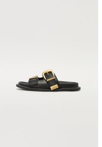 Black leather slide sandal featuring two adjustable straps with gold buckles, a textured footbed, and a flat rubber sole.