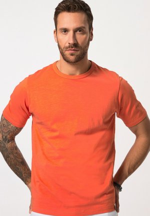 Tričko s krátkým rukávem a kulatým výstřihem v jasně oranžové barvě s hladkým povrchem. Má jemné variace barvy a volný střih.