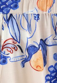 Lys stof med et blomster- og abstrakt mønster i blå, orange og rød på en cremefarvet baggrund; blød tekstur med en glat overflade.