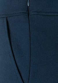 Navy blauwe leggings met een gladde textuur, een aansluitend ontwerp en een zichtbare ritssluiting langs de achternaad voor extra functionaliteit.