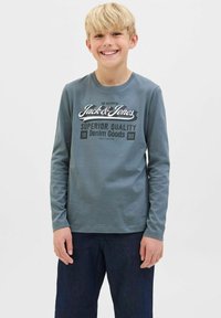 Kratak rukav, košulja od pamuka plave-sive boje sa grafičkim printom u crnoj i bijeloj boji s natpisom "Jack & Jones" i "Superior Quality Denim Goods."
