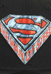 Schwarze Baseballmütze mit einem gestickten Superman-Logo. Das Design umfasst ein blau-rotes Farbschema mit dynamischen Akzenten und Text.