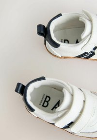 Scarpe da neonato bianche con dettagli blu navy, due cinturini in Velcro e suola color cognac. Include una linguetta per tirare e un'etichetta interna con la taglia (0-3 mesi).