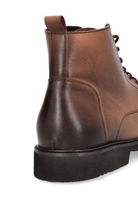 Brązowy skórzany botek za kostkę z gładkim wykończeniem, okrągłym kształtem, wzmocnionymi szwami i teksturowaną gumową podeszwą. Zawiera uchwyt do zakładania.
