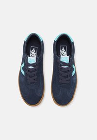 Námořnické kožené tenisky s světlými modrými akcenty, hnědou gumovou podrážkou, zaoblenou špičkou a odpovídajícími tkaničkami. Klasické logo Vans na stélce.