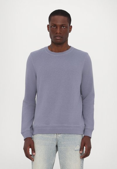 Hellblauer Pullover mit Rundhalsausschnitt, langen Ärmeln und gerippten Bündchen und Saum. Weicher Stoff mit subtiler Textur, kombiniert mit blauen Jeans.