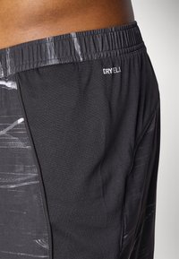 Schwarze Sportshorts mit strukturierter Oberfläche, die ein dezentes grafisches Muster aufweisen. Elastischer Bund mit dem weißen "DRYELL"-Logo.