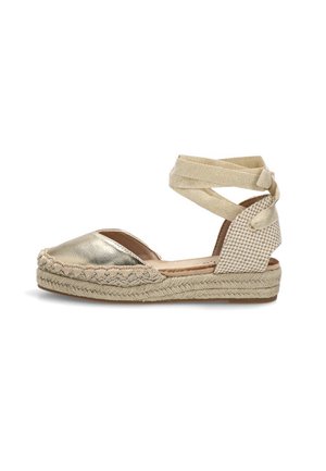 Zapato plano estilo esparto con puntera metálica, suela de yute tejida, tacón a cuadros y cierre de lazo beige para atar en el tobillo.