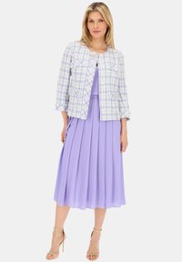 Jasny niebieski i biały płaszcz w kratę z dwóch przednich kieszeni, zestawiony z pastelową fioletową plisowaną sukienką. Całość dopełniają beżowe sandały na obcasie.