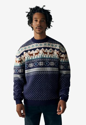 Pull en tricot marin avec des motifs d'hiver, des motifs de rennes, des flocons de neige et des accents géométriques dans des tons crème et bleu.