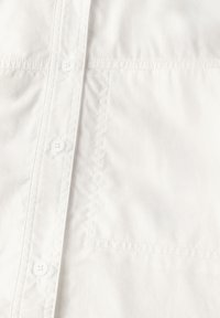Camicia bianca con bottoni, caratterizzata da una sottile texture, taschino a toppa e cuciture a contrasto lungo le giunture. Design classico con chiusura a bottoni standard.