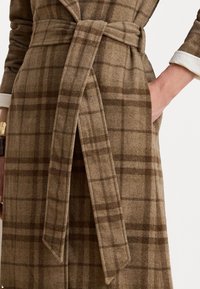 Cappotto avvolgente a quadri marroni con cintura, collare e tasche laterali. Realizzato in un tessuto misto lana texturizzato.