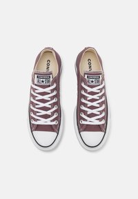 Bordeauxfarbene Leinensneaker mit weißen Schnürsenkeln, schwarzen Gummidetails und einer weißen Zehenkappe mit einem Logopatch auf der Zunge.