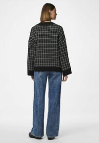 Kootud must särk valge ruudustiku mustriga, ümar kaelus ja soonikkoes varrukad. Kombineeritud helesiniste laiade jänesinäoga teksadega.